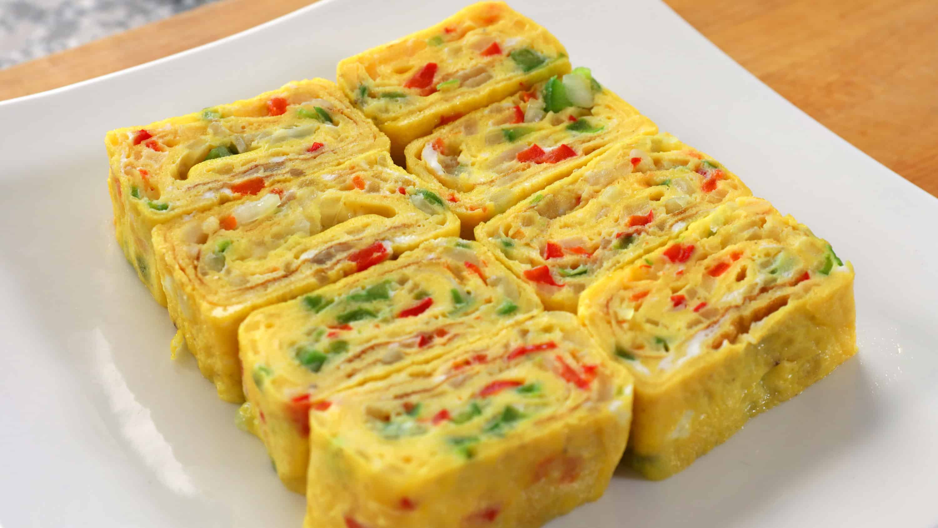 Sliced Korean rolled omelette gyeran mari showing the spiral layers of yellow egg with chopped vegetables inside
