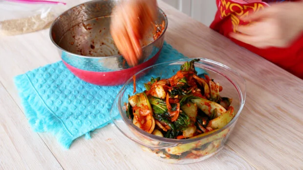 Adding bok choy kimchi to the container