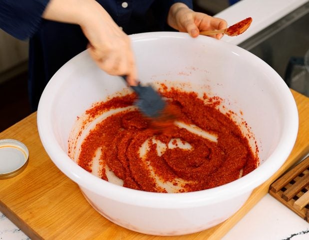 adding gochugaru to kimchi paste